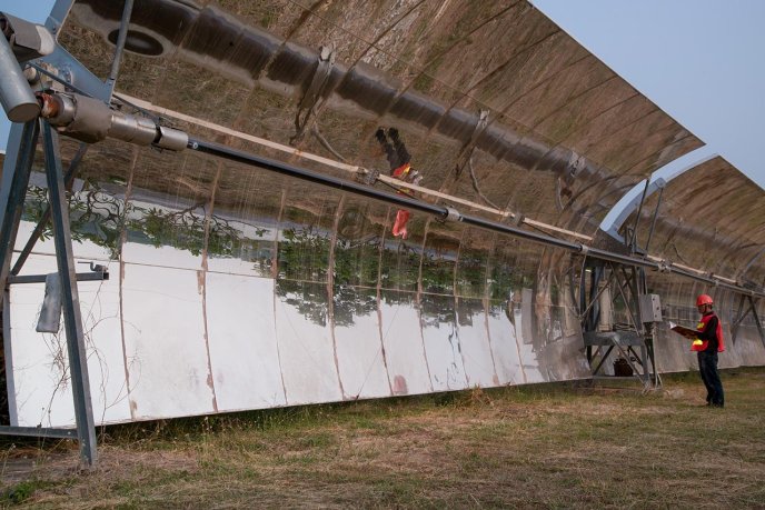 Worker at a tilted parabolic trough solar collector. (Source: © topten22photo / stock.adobe.com)